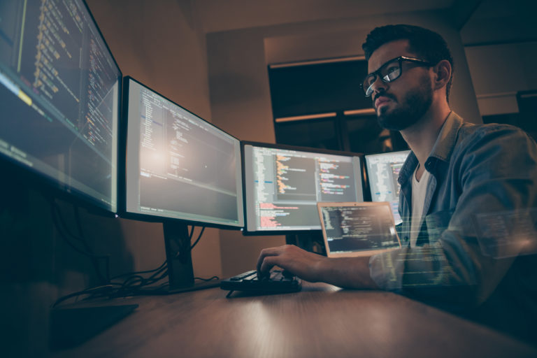 Profile side view of nice attractive serious skilled qualified smart clever bearded brunet guy nerd building fixing extracting file editing framework web design in dark beige room workplace station