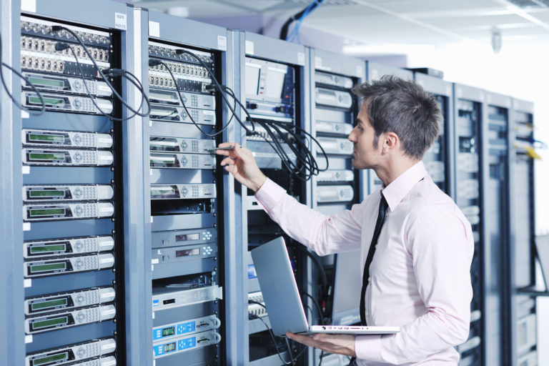 young engeneer business man with thin modern aluminium laptop in network server room